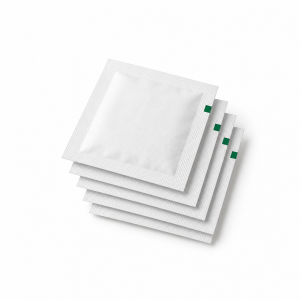 Stack of blank white preparation-pad sachets with small deep green edge marks on a white background.